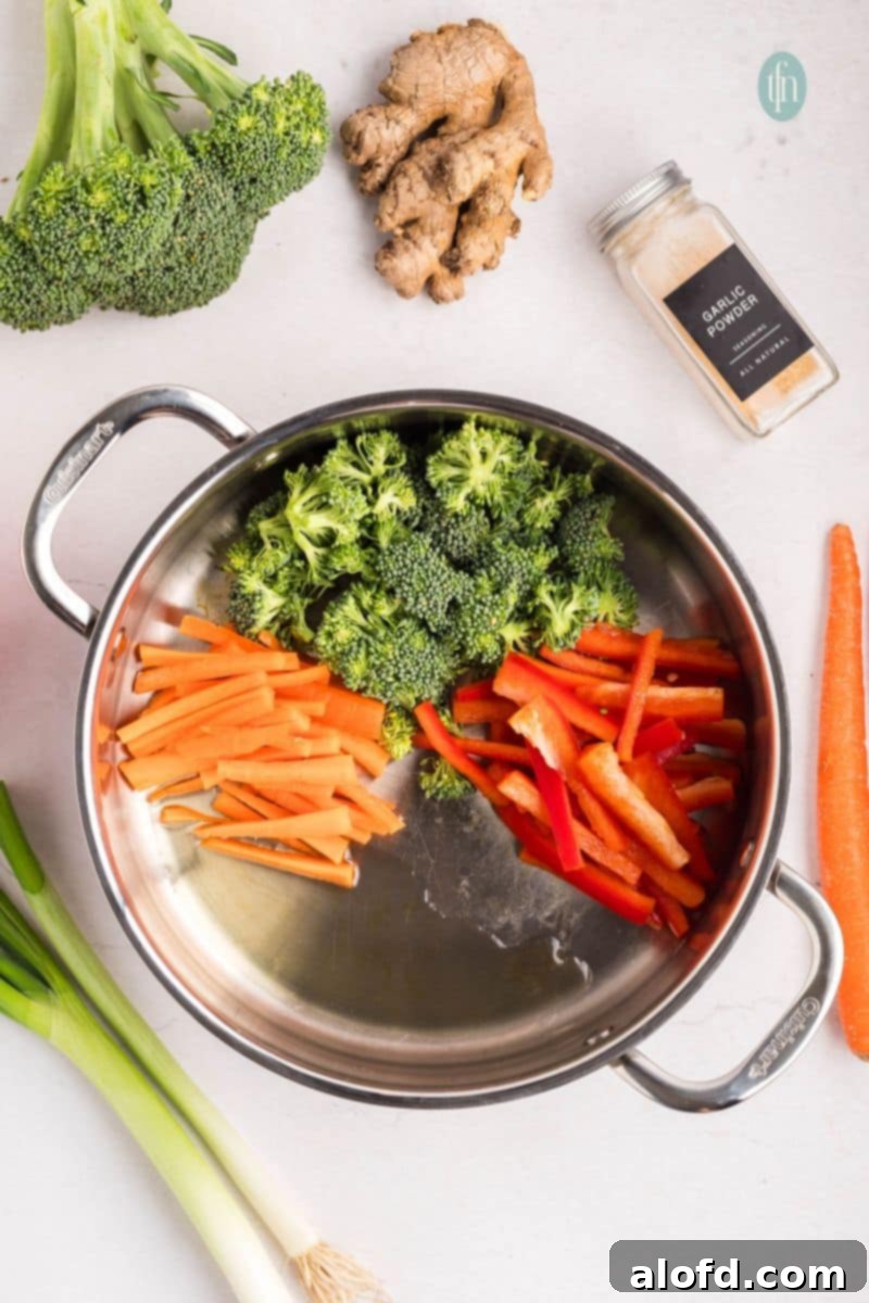 Chopped vegetables simmering in a pan with oil.