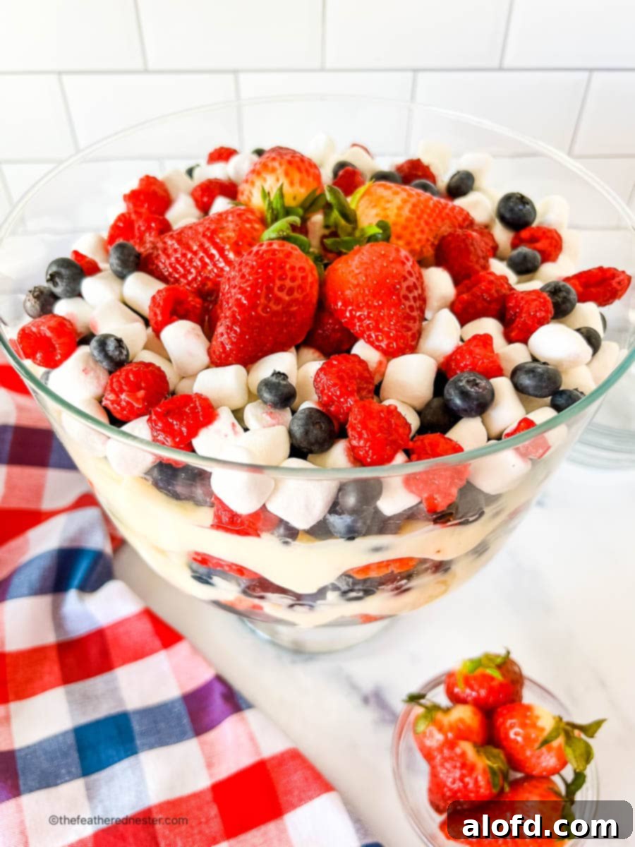cheesecake 4th of July salad in a large serving bowl next to a 4th of July table cloth. A vibrant and festive dessert.