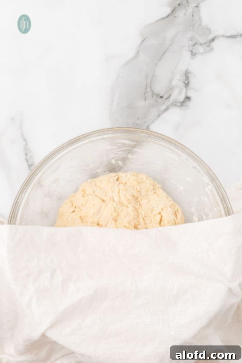 A glass bowl with dough covered with cloth.