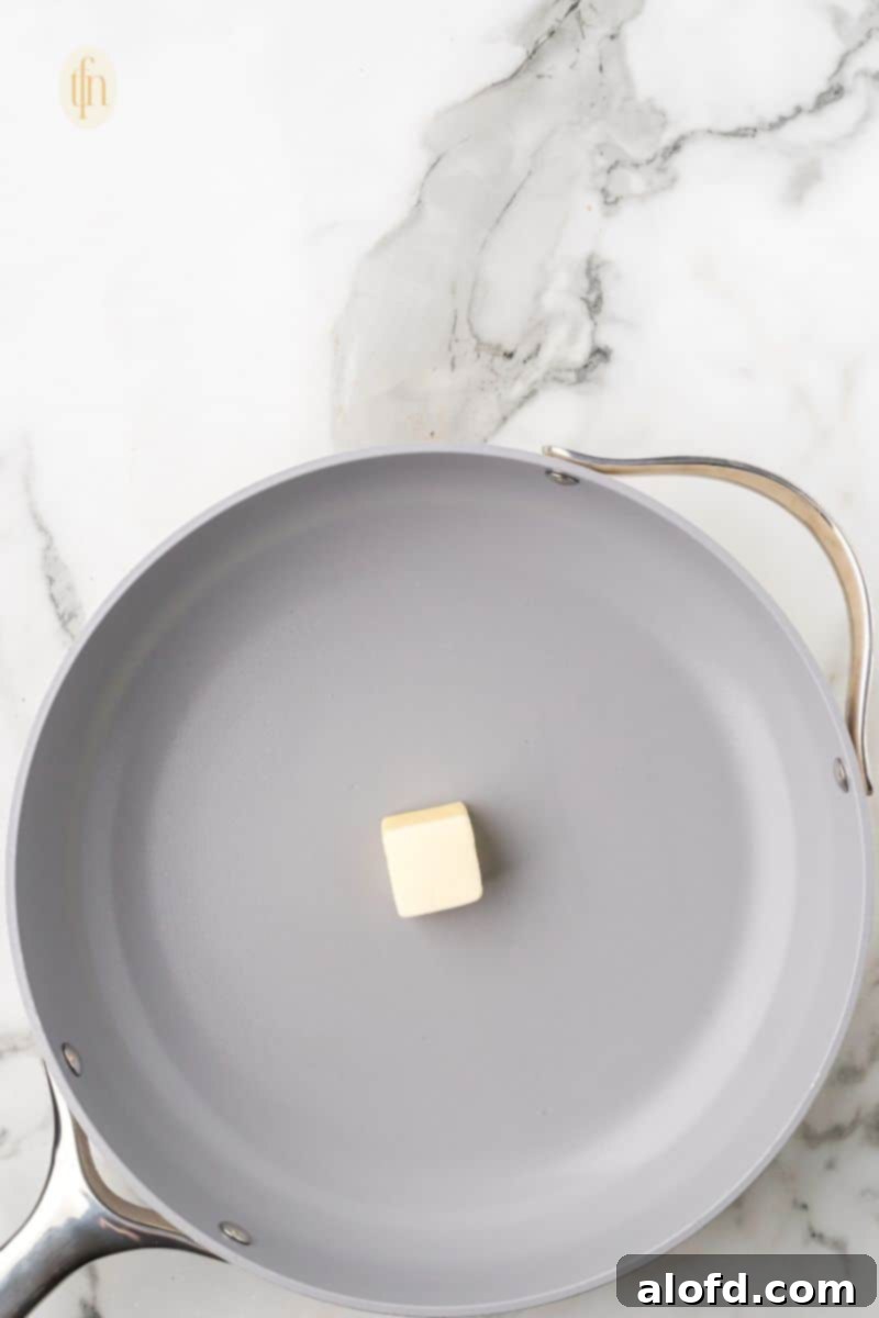 Zesty Lemon Chicken Orzo Pasta 11 A frying pan on a stove with perfectly melted butter, ready for the next step of searing the chicken.