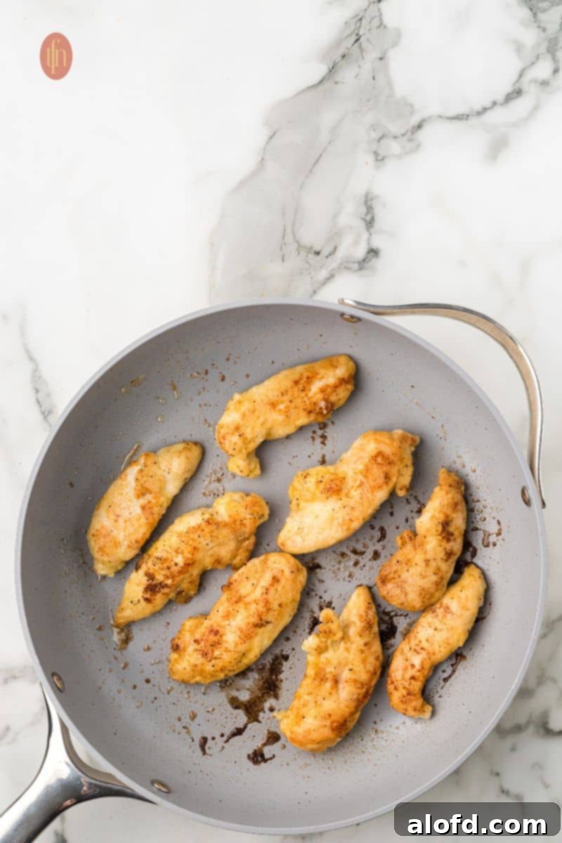 Zesty Lemon Chicken Orzo Pasta 13 Perfectly cooked, golden-brown chicken pieces resting in a frying pan after searing, indicating they are ready to be set aside.
