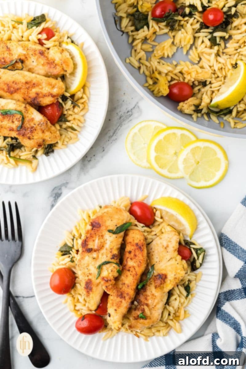 Zesty Lemon Chicken Orzo Pasta 24 A close-up of a single serving of lemon chicken orzo pasta on a white plate, beautifully composed with chicken, orzo, and vegetables, garnished for presentation.