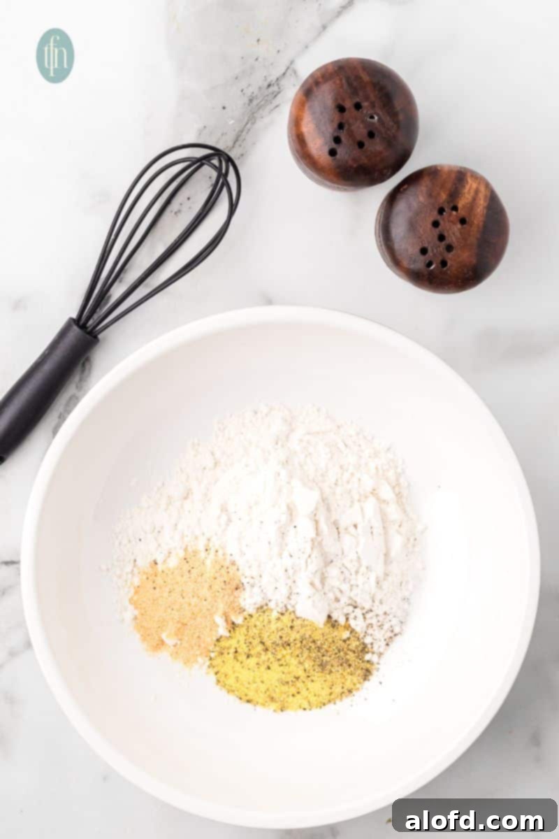 Zesty Lemon Chicken Orzo Pasta 7 A culinary setup featuring a bowl of dry spice mixture, alongside salt and pepper shakers and a whisk, highlighting the preparation of seasonings.