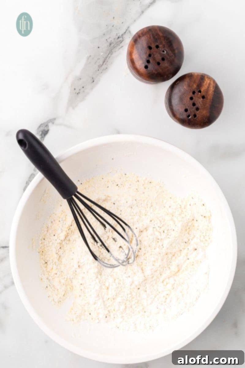 Zesty Lemon Chicken Orzo Pasta 8 A close-up view of a bowl of dry ingredients, featuring a whisk resting inside, illustrating the well-mixed texture of the seasoning blend.