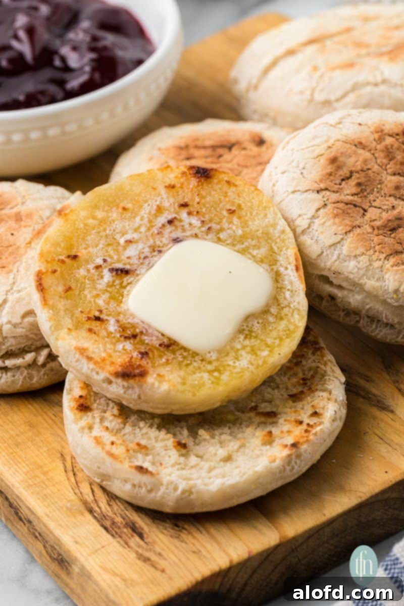 Artisan Sourdough English Muffin Bread 2 A platter of golden-brown sourdough English muffins with melting butter on top, ready to be enjoyed for breakfast.