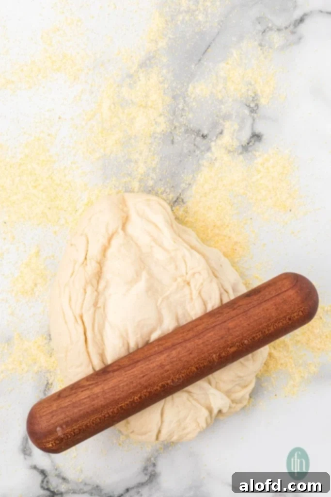 Artisan Sourdough English Muffin Bread 14 A flour-covered surface with a ball of dough and a rolling pin, ready for shaping.