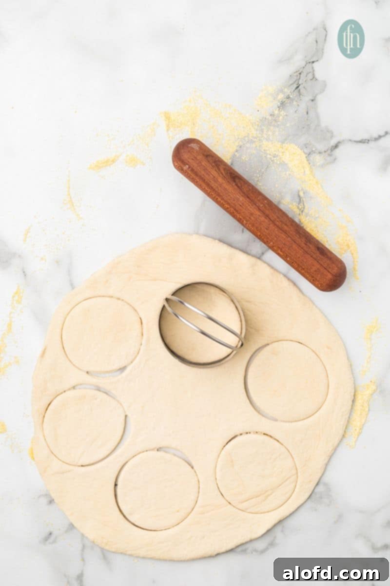 Artisan Sourdough English Muffin Bread 16 More detail of rolled dough with a cookie cutter and rolling pin, showing the cutting process.