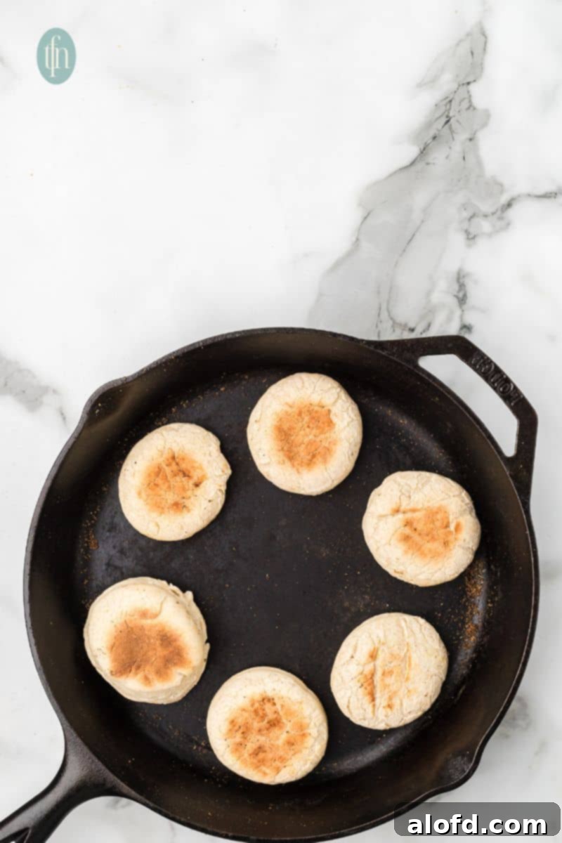 Artisan Sourdough English Muffin Bread 20 Beautifully baked English muffins sizzling in a skillet, showcasing their golden crust.