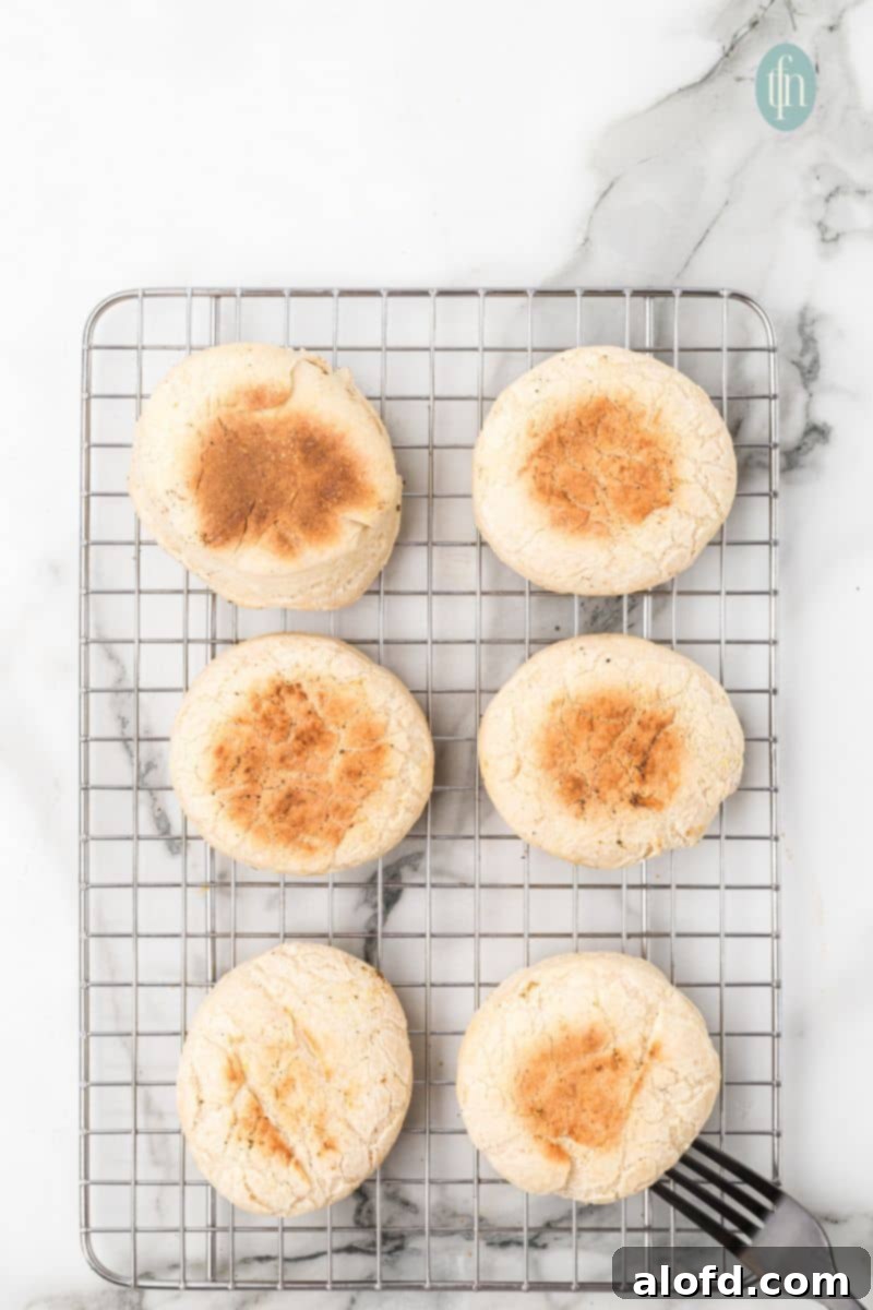 Artisan Sourdough English Muffin Bread 21 Sourdough English muffins cooling on a wire rack after being cooked.