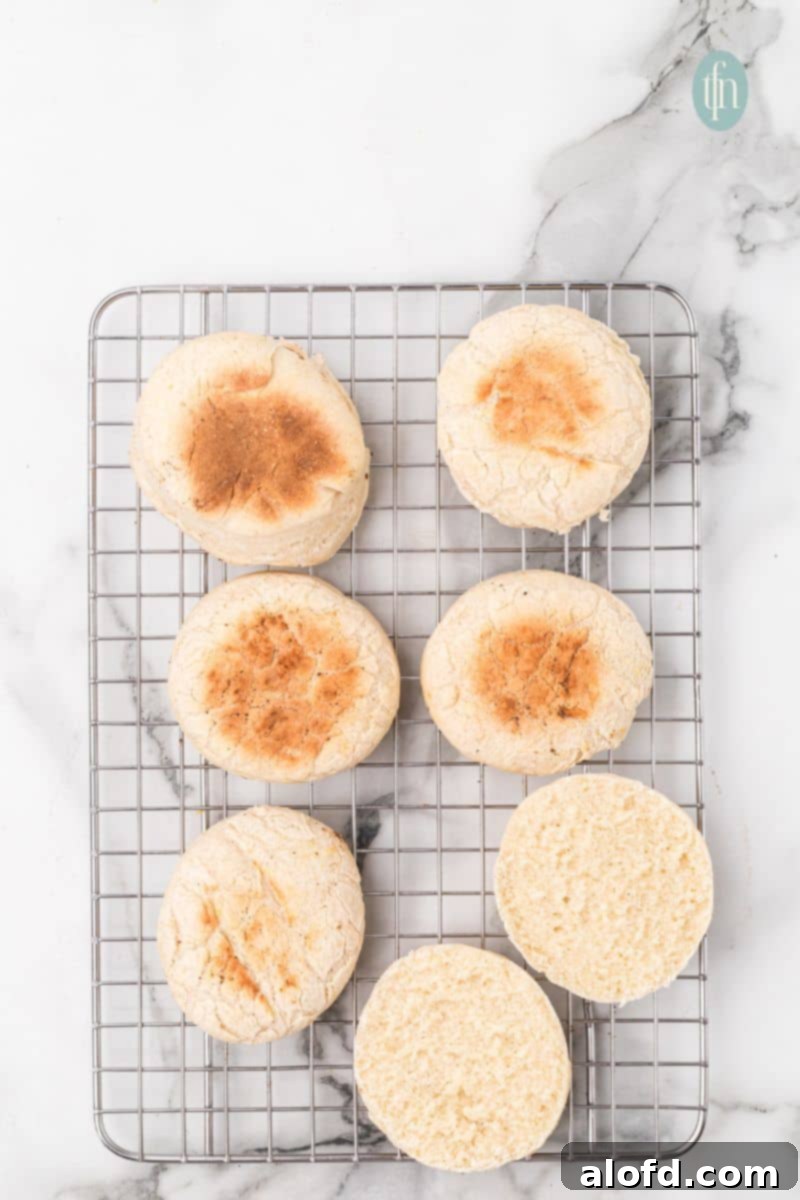 Artisan Sourdough English Muffin Bread 22 More English muffins cooling on a wire rack, showcasing their uniform golden color.