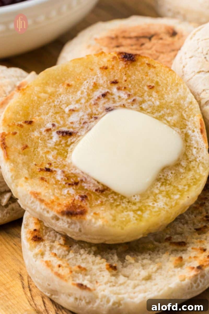 Artisan Sourdough English Muffin Bread 23 A single sourdough English muffin, perfectly split and topped with a pat of butter, ready to be eaten.