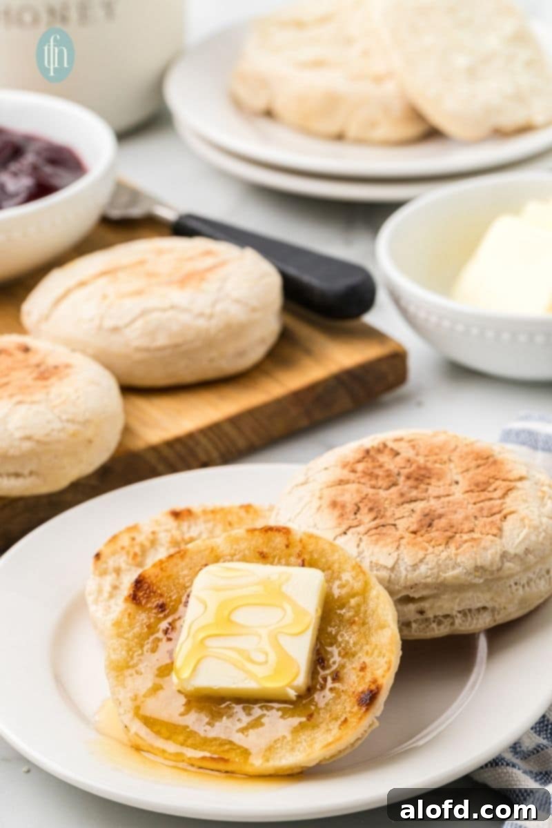 Artisan Sourdough English Muffin Bread 24 A single sourdough English muffin, beautifully split and topped with melting butter, inviting a delicious bite.