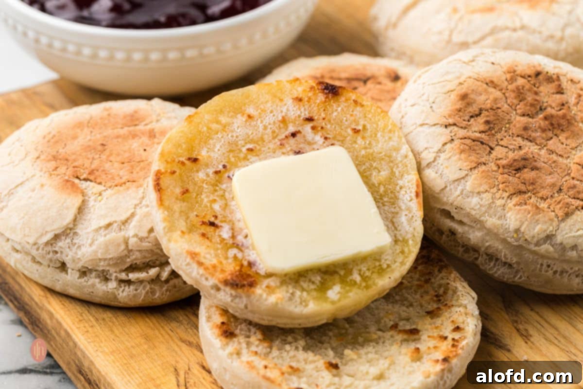 Artisan Sourdough English Muffin Bread 25 A horizontal shot of a split English muffin with melting butter, highlighting its porous texture.