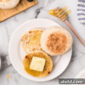 Artisan Sourdough English Muffin Bread 26 A plate of fluffy sourdough English muffins with melting butter, ready for breakfast.