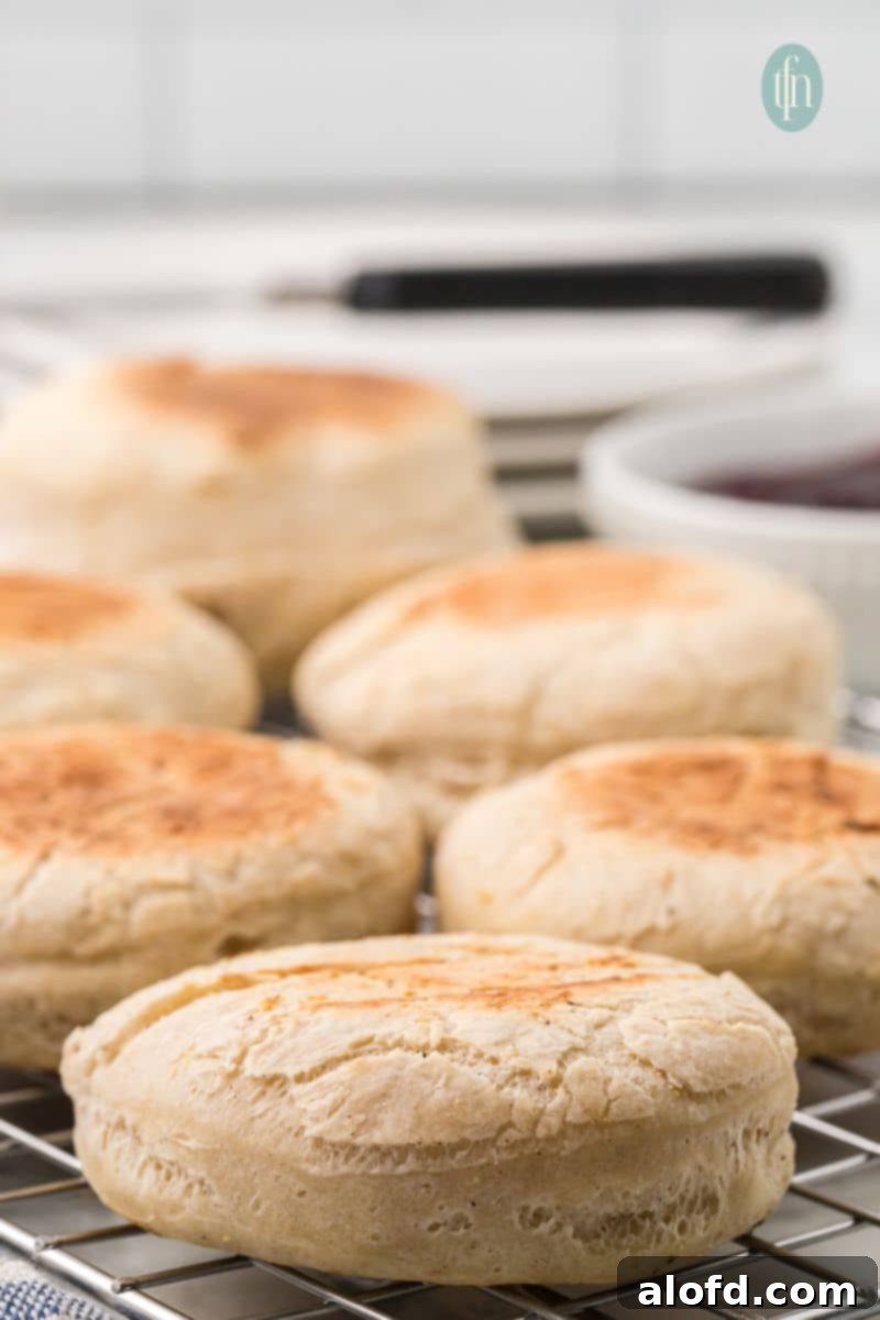 Artisan Sourdough English Muffin Bread 6 Freshly cooked English muffins cooling on a wire rack, steam gently rising.