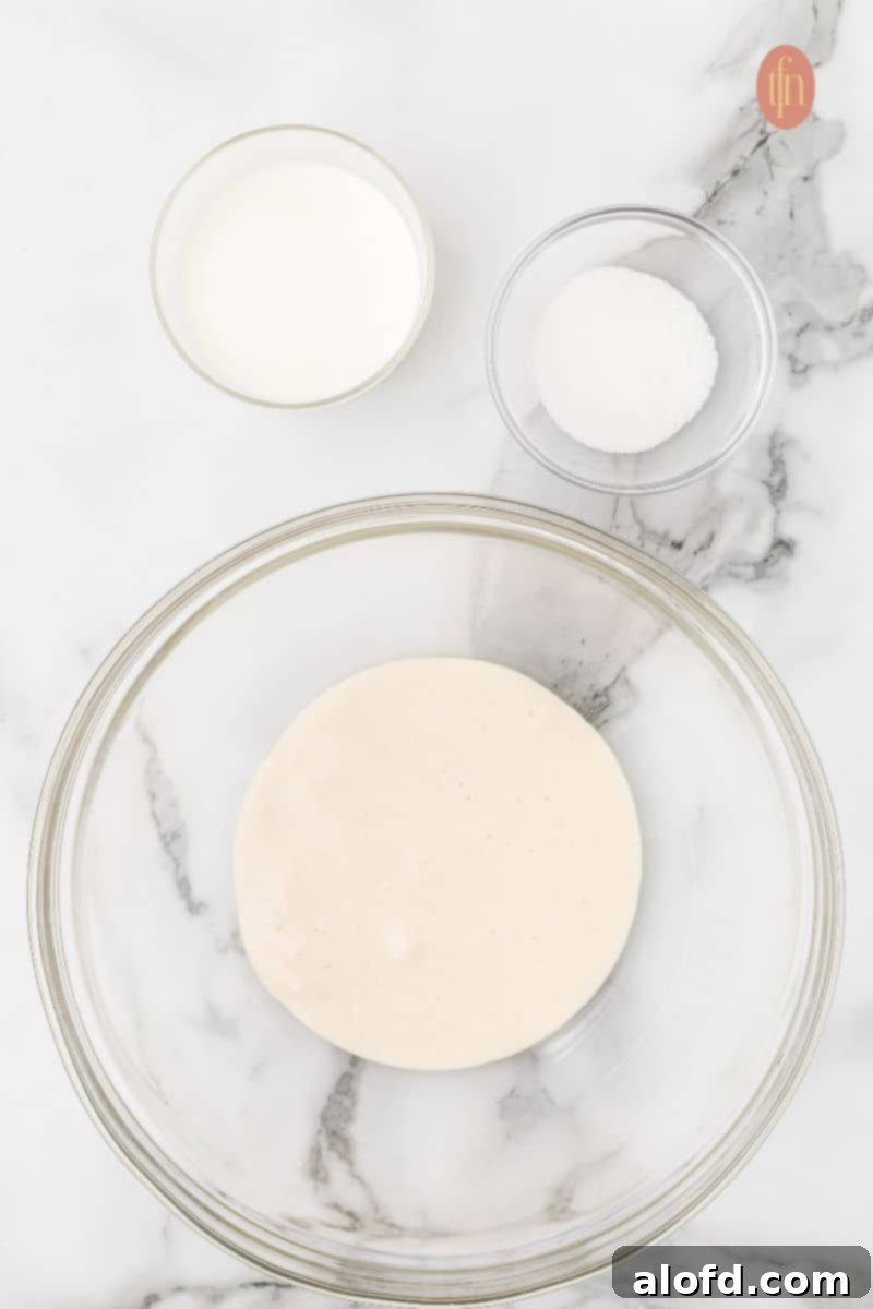 Artisan Sourdough English Muffin Bread 7 A bowl containing sourdough starter, milk, and sugar, ready for mixing.