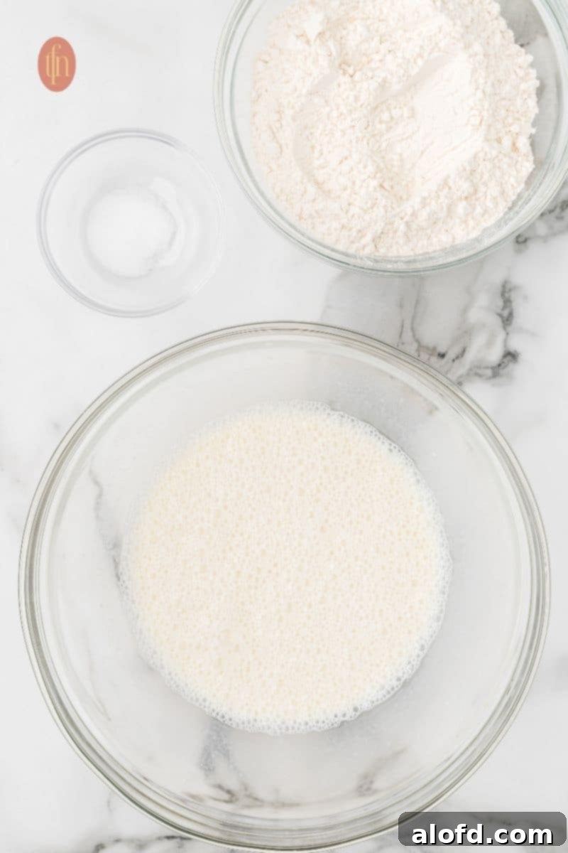 Artisan Sourdough English Muffin Bread 9 A bowl showcasing the white liquid mixture, salt, and flour, poised for the next mixing stage.