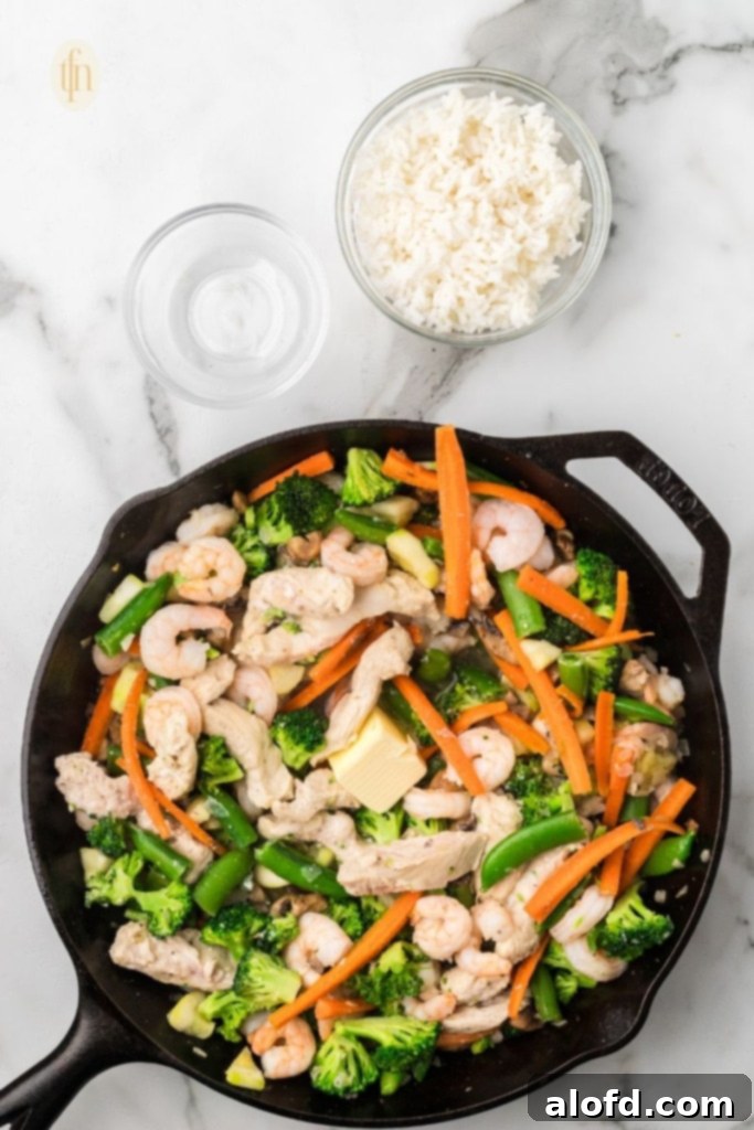 Surf and Turf Fried Rice 11 Stirring the rice to coat it in butter with the chicken, shrimp, and vegetables.