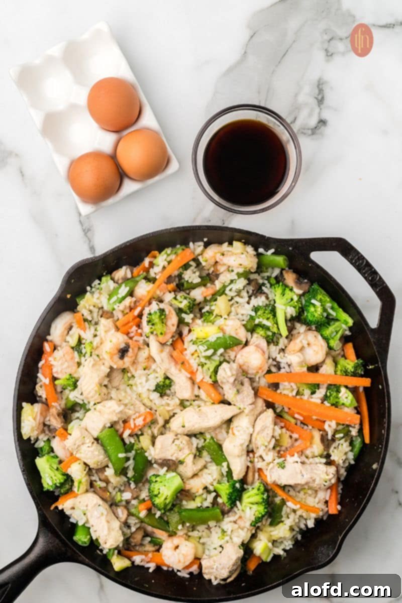 Surf and Turf Fried Rice 12 Pouring soy sauce over the fried rice mixture in the skillet.
