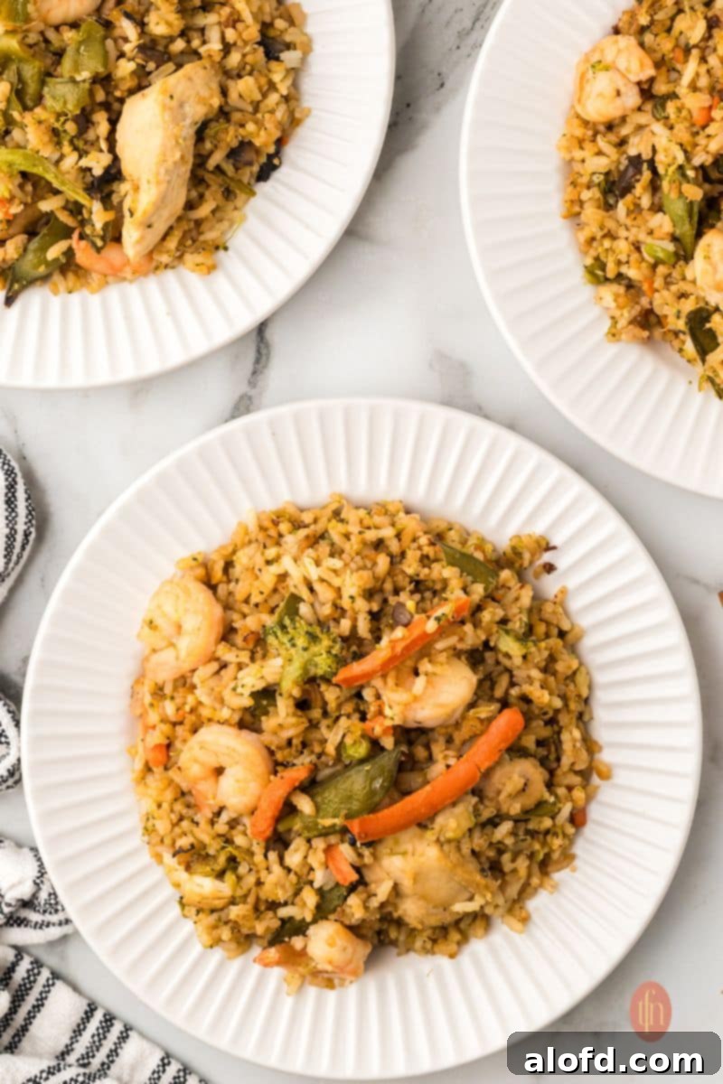 Surf and Turf Fried Rice 17 Three elegant plates of shrimp and chicken fried rice, garnished with fresh herbs, suggesting a formal or festive meal.