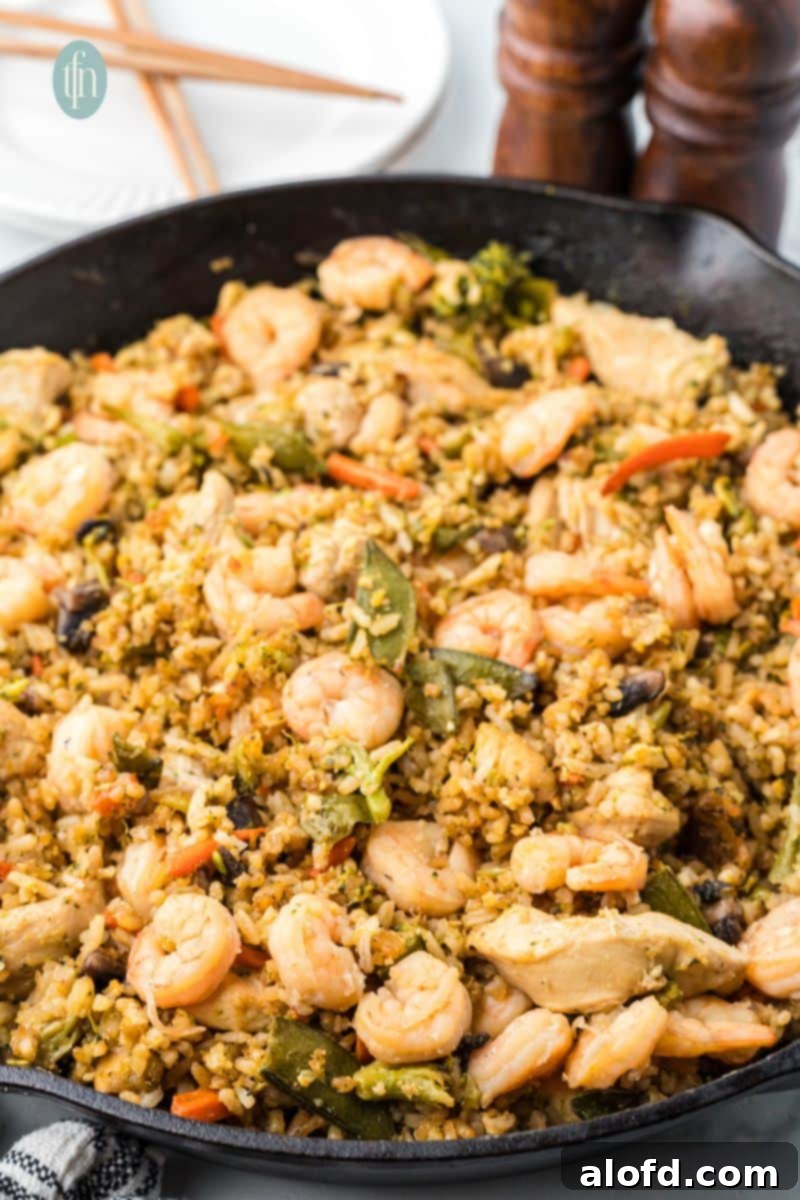 Surf and Turf Fried Rice 5 A large skillet filled with perfectly cooked shrimp and chicken fried rice, steam rising, ready to be served.