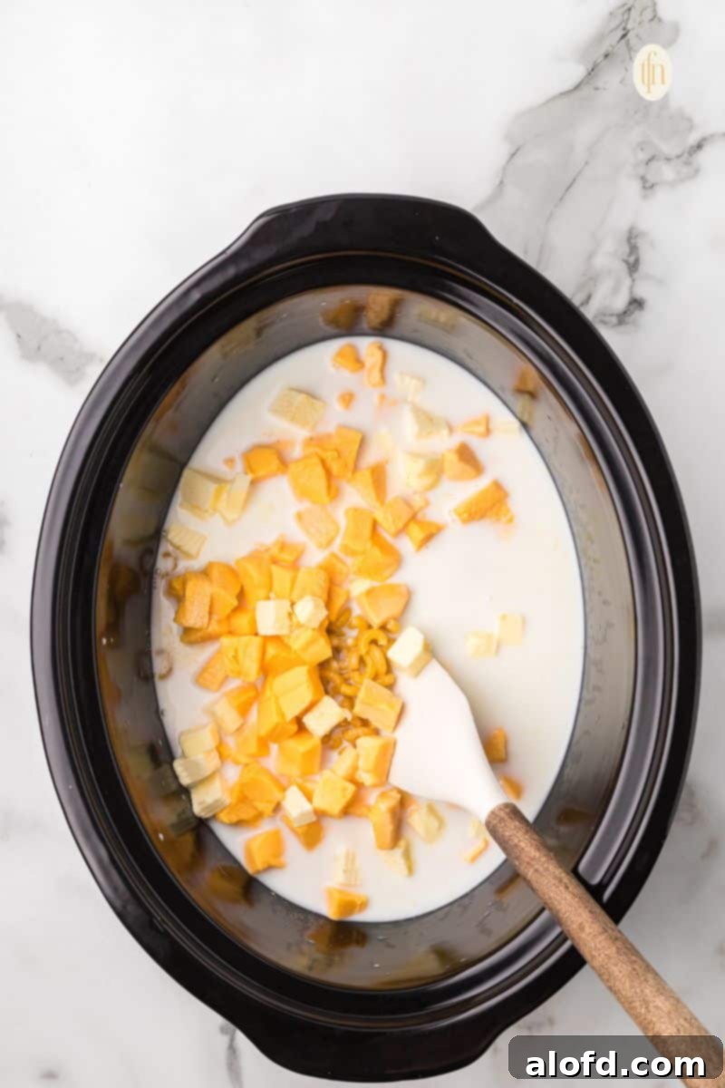 Crockpot with macaroni mixture and a ladle for stirring.