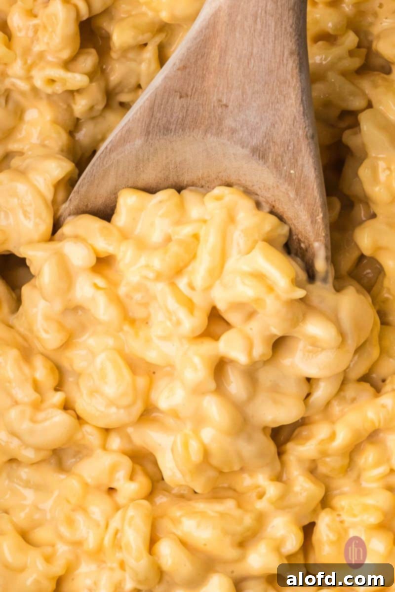 A scoop of Velveeta mac and cheese being lifted from the crockpot.