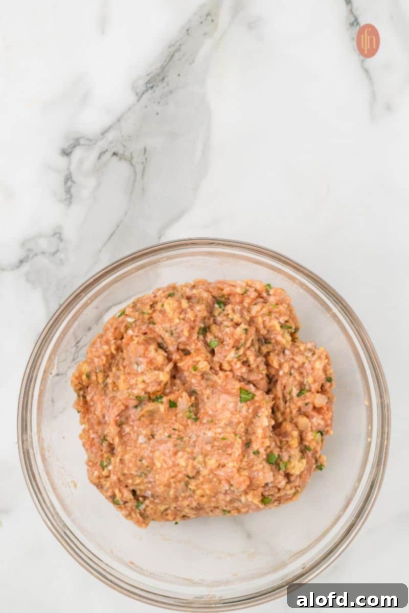 Savory Chicken Meatloaf 12 A large glass bowl holds the finished raw chicken meatloaf mixture, which is uniformly combined and ready to be shaped.