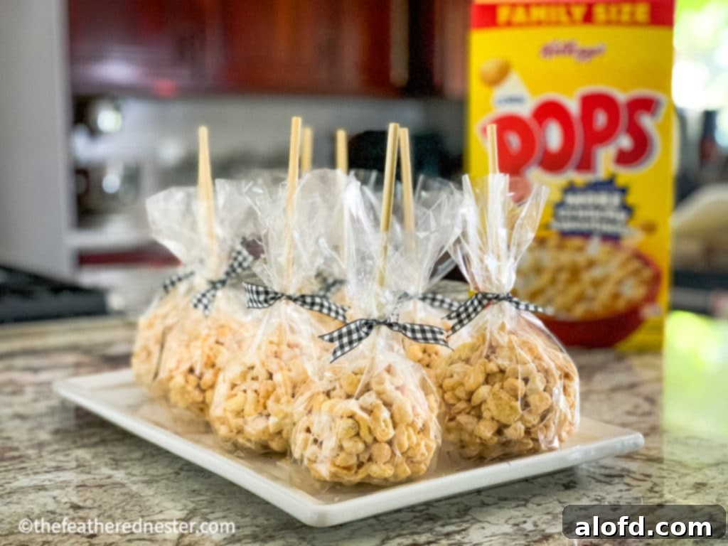 Assorted fall-themed goodies for Halloween, including Corn Pops marshmallow treats shaped into balls with sticks, arranged on a rustic wooden tray with small pumpkins and leaves.