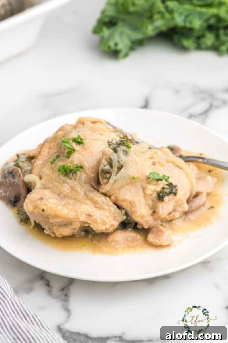 Comforting Crockpot Smothered Chicken 2 Crockpot creamy smothered chicken on a white plate, garnished with fresh herbs.
