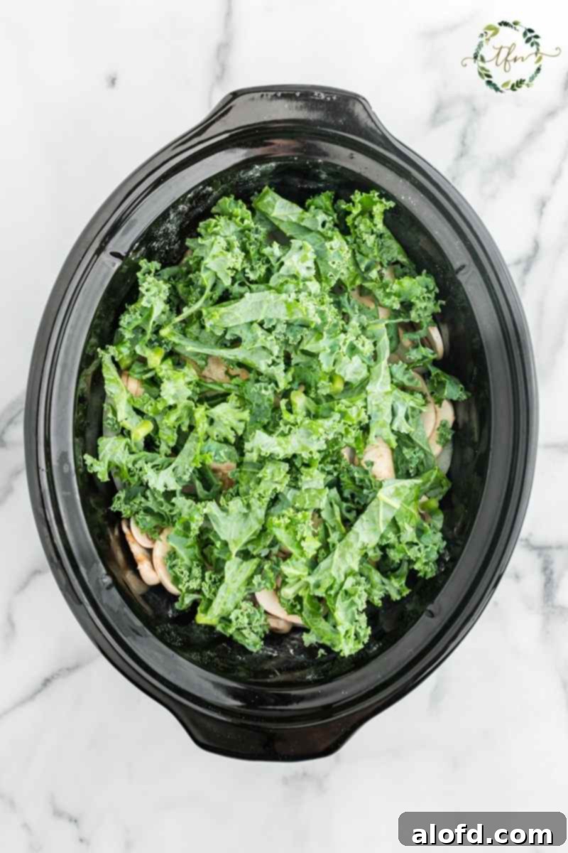 Comforting Crockpot Smothered Chicken 7 Crockpot filled with chicken, onions, and kale, simmering to perfection.
