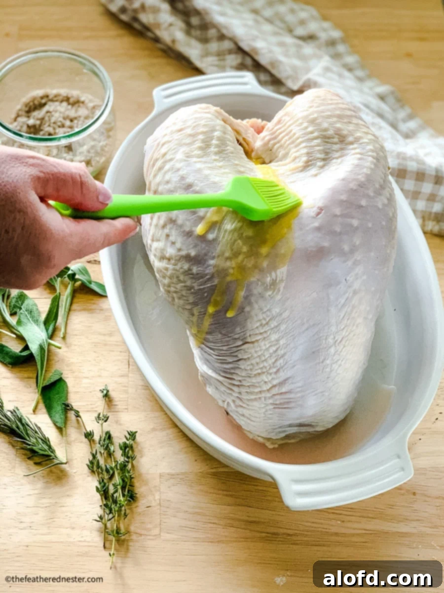 Tender Buttermilk Turkey Breast 5 A chef brushing melted butter over the skin of an uncooked, brined turkey breast before roasting, enhancing its potential for a golden, crispy finish.