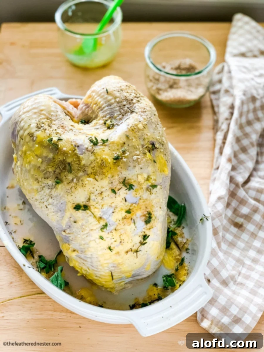 Tender Buttermilk Turkey Breast 7 A raw turkey breast, generously brushed with melted butter, placed on a roasting rack in a pan, ready for the oven.