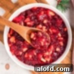 Jello mixture in a white bowl with wooden spoon.