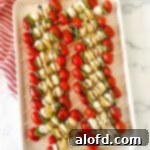 a white tray of kabob party appetizers with balsamic glaze on top of a red and white napkin.