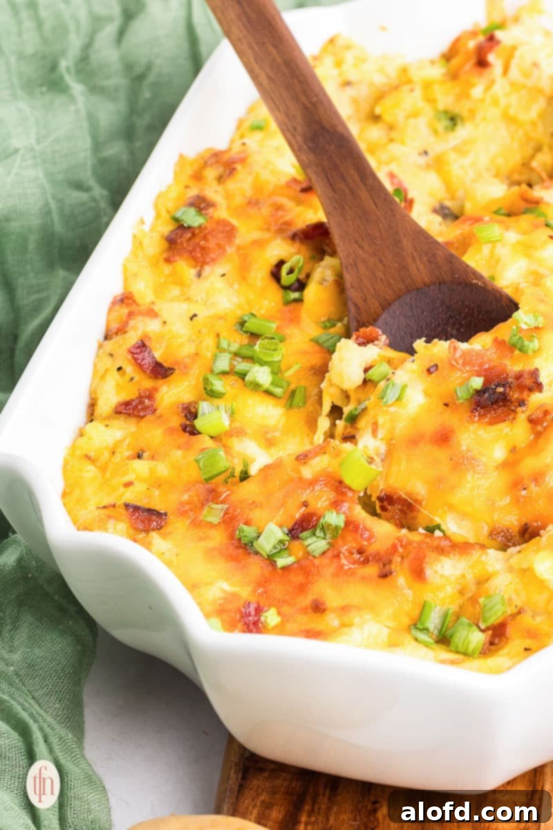 Baked mashed potatoes in a casserole dish with a wooden spoon.