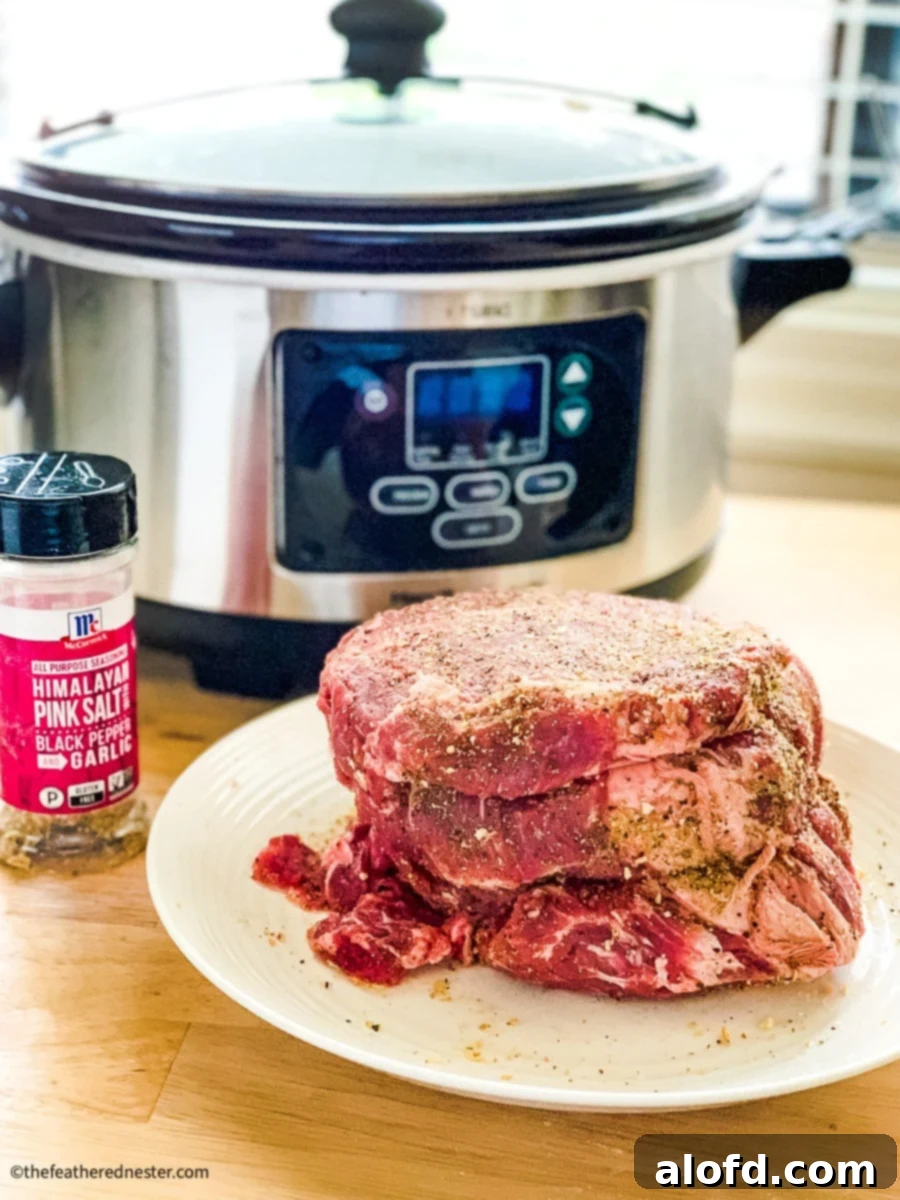 Fall-Apart Slow Cooker Pot Roast 4 Seasoned beef roast with a slow cooker and a container of McCormick all-purpose seasoning in the background.