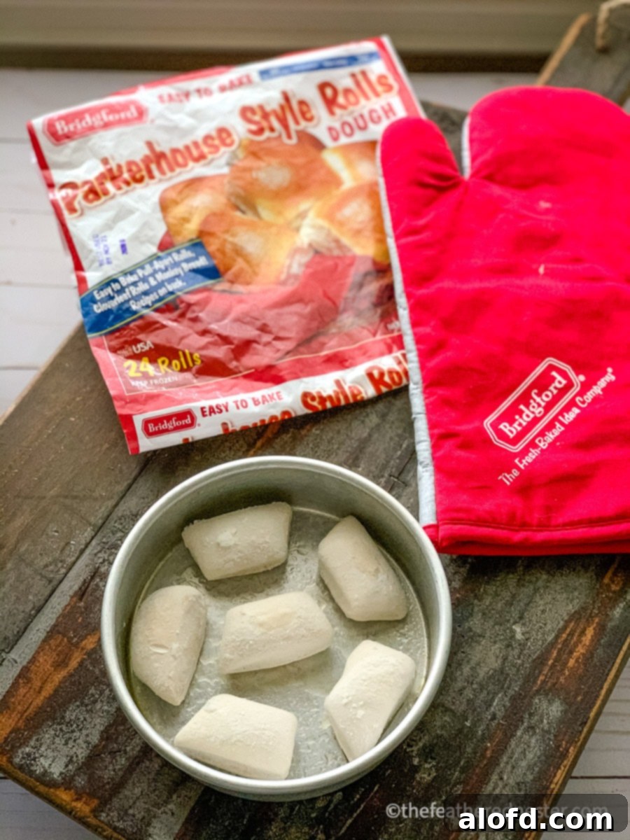Frozen dinner rolls arranged in a baking pan to thaw, with a package of Bridgford Parkerhouse style rolls visible in the background, highlighting the convenience of frozen dough.