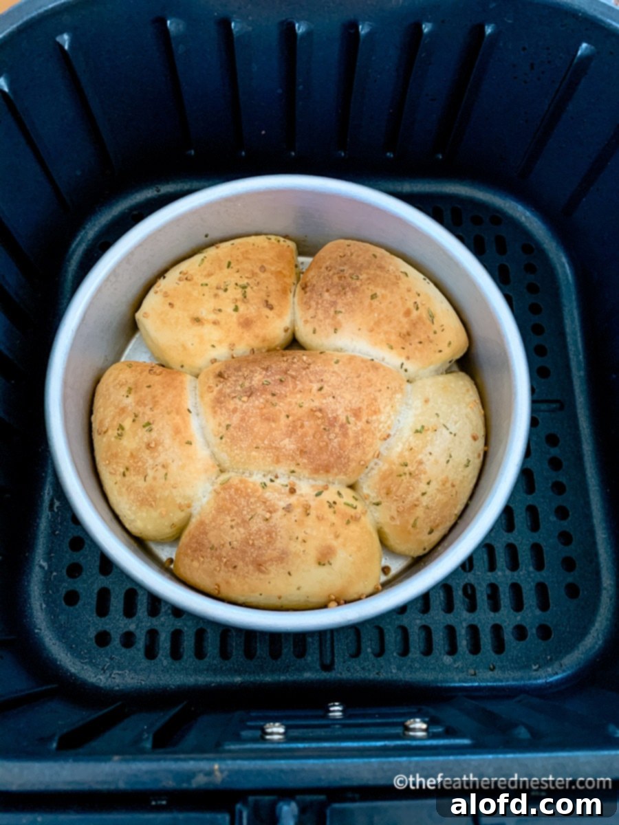 Easy air fryer dinner rolls made from frozen rolls recipes, shown golden brown and fluffy in a small baking dish, ready to serve.