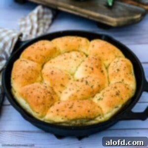Freshly baked rosemary garlic dinner rolls in a cast iron skillet.
