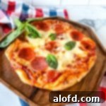 a fire grilled pizza on a wooden serving tray with a sprig of basil and a red, white, and blue napkin in the background.