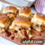 Five BBQ chicken slider sandwiches on a wood serving board.