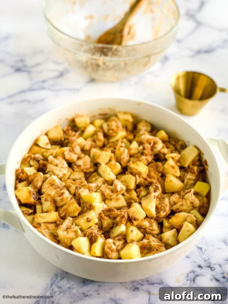 Chopped Bridgford Ready-Dough and diced apples tossed with cinnamon and brown sugar in a casserole dish, ready for baking.