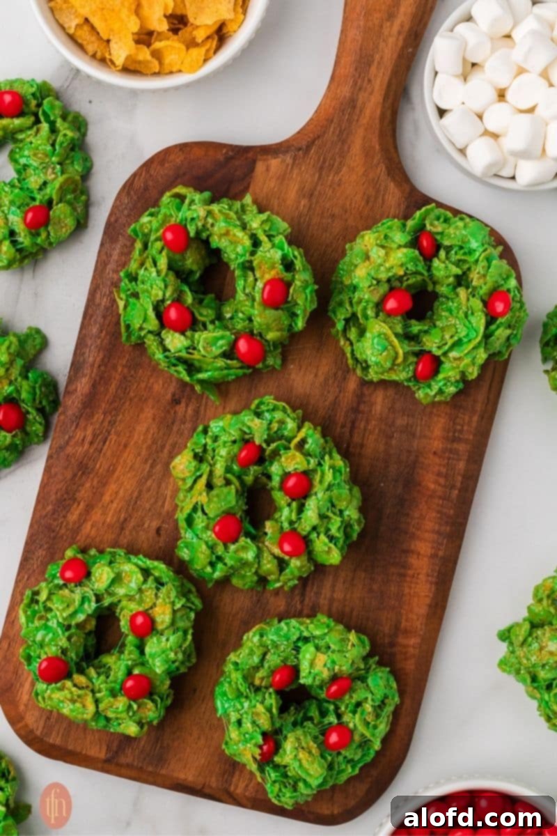 Christmas Wreath Cereal Cookies 3 Ingredients for No-Bake Christmas Cornflake Wreath Cookies including cornflakes, mini marshmallows, and red cinnamon candies.