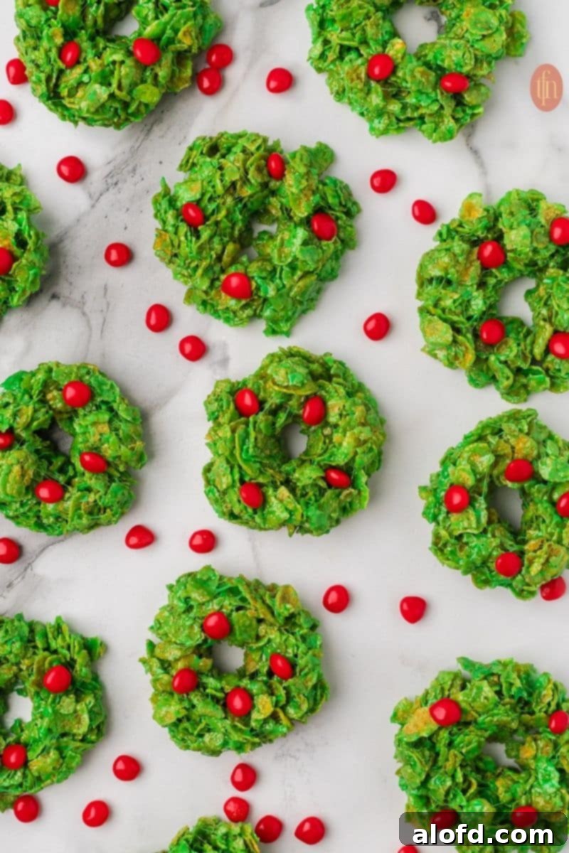 Christmas Wreath Cereal Cookies 5 Close-up of beautiful No-Bake Christmas Cornflake Wreath Cookies with bright red cinnamon candies on top.