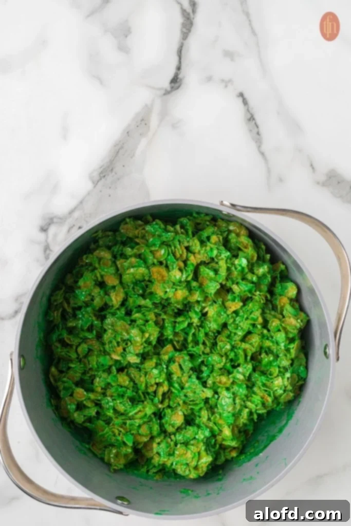 Christmas Wreath Cereal Cookies 8 The cornflake cereal being folded into the melted marshmallow and green food coloring mixture.