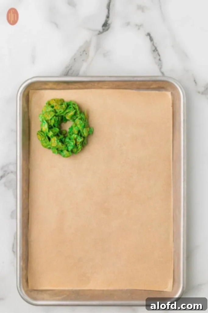 Christmas Wreath Cereal Cookies 9 A baking sheet filled with vibrant green cornflake wreaths ready for decoration.