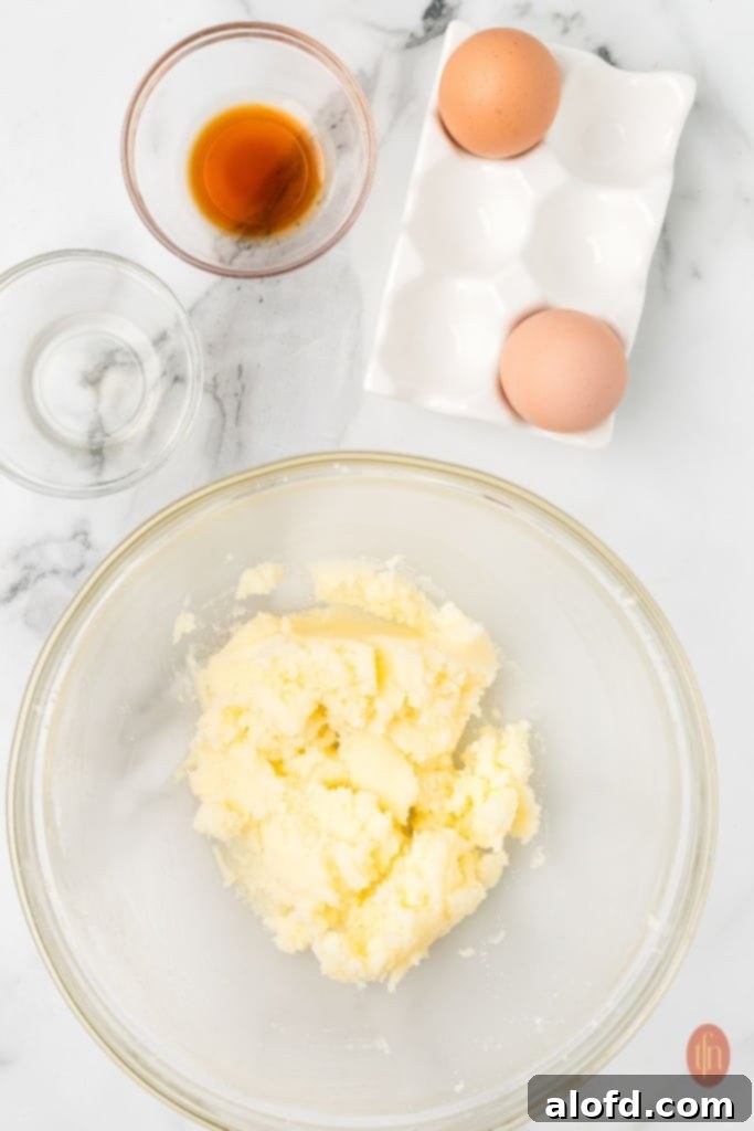 A visually appealing arrangement featuring a bowl of dough mixture, accompanied by a bowl of vanilla extract, peppermint extract, and eggs, showcasing the wet ingredients used in the recipe.