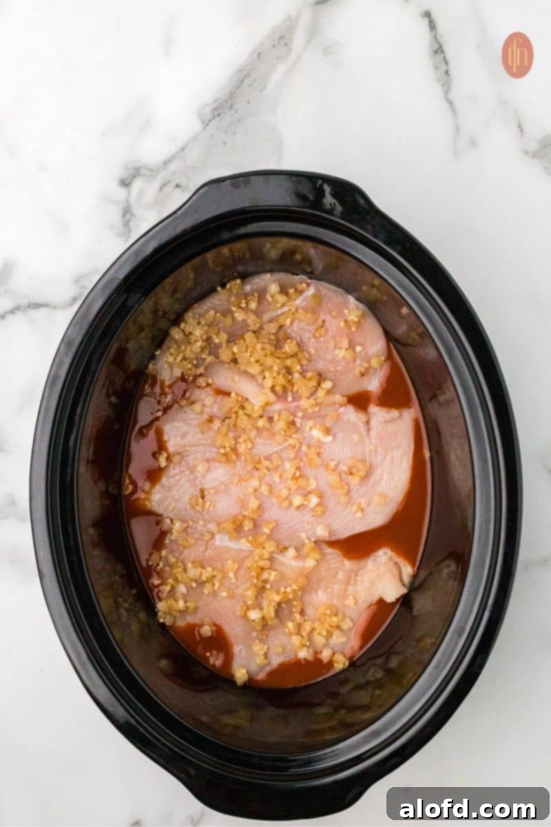 Sautéed onion mixture being spooned over the chicken breasts.