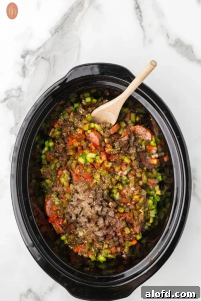 Slow-Cooker Sausage and Potato Delight 12 Full crockpot with ingredients for slow cooker sausage and potatoes.